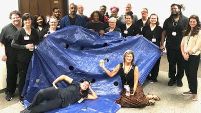 Division of Laboratory Animal Medicine stop for a photo with the blue tarp they used during a team building exercise.