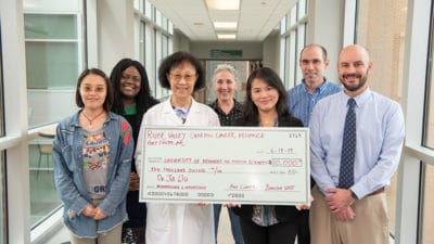 Jia Liu, Ph.D., right, and Shuk-mei Ho, Ph.D., hold up a large facsimile of a $10,000 check in celebration of the donation from the River Valley Ovarian Cancer Alliance.