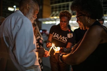 Attendees at a September vigil marking the passing of Edith Irby Jones light their candles.