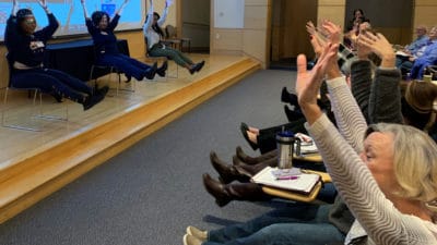 Regina Gibson, center stage, and two assistants lead the audience through a few Ageless Grace exercises during the Dementia Update at the UAMS Donald W. Reynolds Institute on Aging.