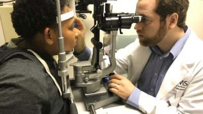 UAMS Medical Student John Musser checks the vision of a student who visited JEI on MLK Day.