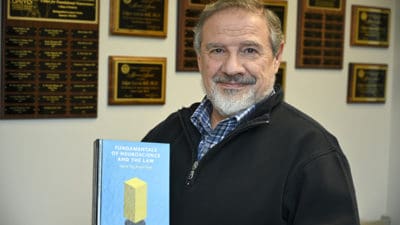 Edgar Garcia-Rill holds a copy of the recently published "Fundamentals of Neuroscience and the Law," which he co-authored with the late Erica Beecher-Monas.