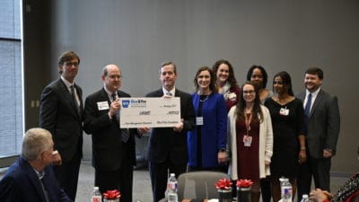 UAMS Chancellor Cam Patterson, M.D., MBA, receives the check from Patrick O'Sullivan, Blue & You Foundation executive director. Beau Blair Jr., UAMS Board of Advisors chair (at left) also accepted along with members of the AR-IMPACT team.