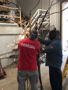 Eric Hale and Kenneth Bailey weld the wrought iron together to make the sculpture.