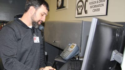 Josh Harper, Pharm.D., a certified specialist in poison information, takes a call while working in the Arkansas Poison and Drug Information Center.
