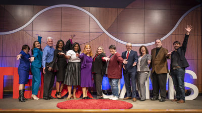The 10 TEDxUAMS presenters and some of team that put on the event celebrate on stage at the end of the day.
