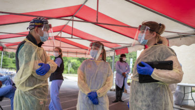 Members of the UAMS mobile triage unit confer before the opening of the COVID-19 drive-thru in East Camden.