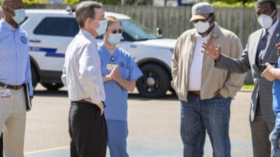UAMS Chancellor Cam Patterson, second from left, talks with Forrest City Mayor Cedric Williams, far right, and State Rep. Reginald Murdock, second from right, April 16 in Forrest City.