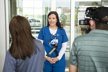 Megan Witzke, R.N., center, answers questions from a local TV reporter on the day before her departure for New York.