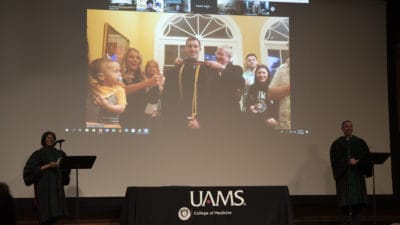Student being hooded with family