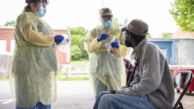 At the Hot Springs drive-thru, Clarence Taylor, seated right, prepares to receive a nasal swab in order to be tested for COVID-19.