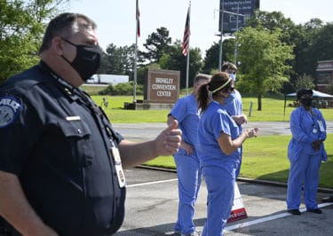 UAMS Police Chief Robert Barrentine, left, gives a thumbs up as Barbara McDonald, APRN, gives instructions to nurse and physician volunteers at the drive-thru in Brinkley.