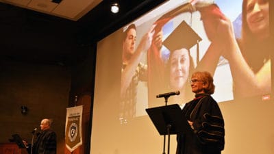 Melanie Reinhardt, Pharm.D., right, and Eddie Dunn, Pharm.D., left, read out the names of College of Pharmacy graduates as each is hooded on live video June 13 at the college's Honors Convocation.