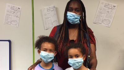 Natasha Gayden, a paraprofessional with the Little Rock School District who usually works with preschool children, cares for Brianna and Tenley Lewis and other students at the UAMS Day Camp at Pulaski Heights Elementary and Middle Schools while the childrens' parents work at UAMS.