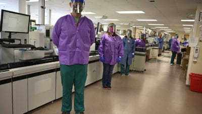 Some of the technologists in the UAMS Clinical Lab stand before the recently upgraded automated testing line. All of them provided input into the planning for the upgrade.