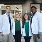 On March 5 before masking and social distancing guidelines were in effect, the NCPA Student Business Plan team stands in front of a pharmacy decorated with signs to stand in for the team's Functional Pharmacy concept they proposed in their winning business plan. Team members are, left to right, Patrick Gurley, Brittany Butterfield, Marissa Johnston and Byron Johnson.