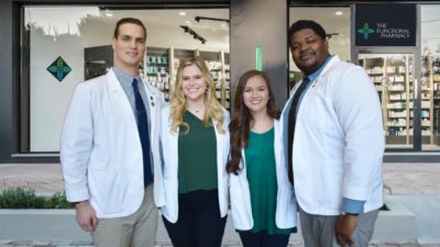 On March 5 before masking and social distancing guidelines were in effect, the NCPA Student Business Plan team stands in front of a pharmacy decorated with signs to stand in for the team's Functional Pharmacy concept they proposed in their winning business plan. Team members are, left to right, Patrick Gurley, Brittany Butterfield, Marissa Johnston and Byron Johnson.
