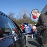 UAMS Chancellor Cam Patterson hands a large tote bag containing masks, hand sanitizer and bilingual information on Covid-19 during a drive-thru event Dec. 22 at Second Baptist Church in Little Rock.