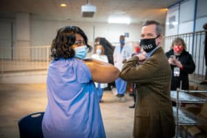 Chancellor Cam Patterson, M.D., MBA, bumps elbows with Yolanda Emery, a medical assistant who was the first UAMS employee to receive the COVID-19 vaccine.