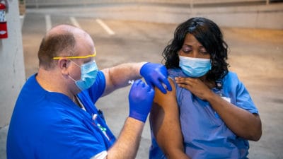 Yolanda Emery, a medical assistant, receives the first COVID-19 vaccine at UAMS in December. Beginning Jan. 19, UAMS will offer the vaccine to Arkansans aged 70 and older as well as teachers and other education workers, including K-12, child care and higher education.