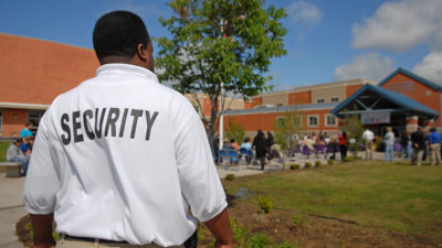 Security guard at a public junior high school -- students OOF in background