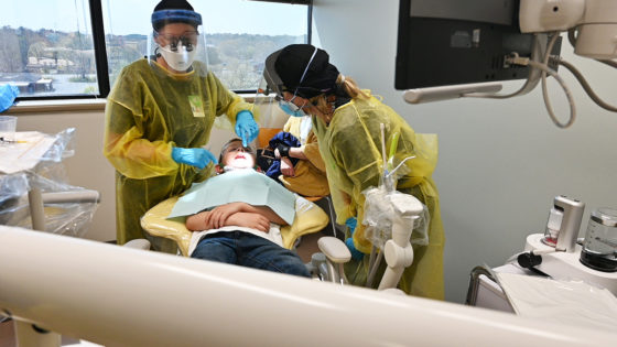 Dental hygiene students do the preparatory work for applying a dental sealant to some of the teeth of one of the 56 children who came to March sealant clinic with their families.
