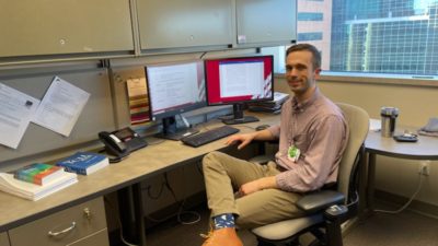 Picture of Reed Gardner, M.D., sitting at his desk in front of his computer in the office he has used throughout the fellowship.