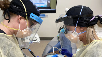 Two dental hygiene students help a patient in a operatory in the new UAMS Dental Hygiene Clinic. All students are supervised by faculty and instructors in the clinic.