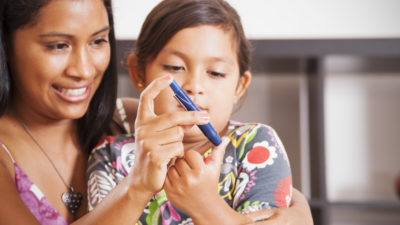 A mother helping her diabetic child monitor her blood sugar. Diabetes mellitus type 1, Juvenile diabetes.