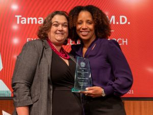 Jessica Snowden, M.D., M.S., MHPTT, (left) congratulates Tamara Perry, M.D., after presenting her with the Excellence in Research Award for her accomplishments as a physician-scientist, including digital health interventions to help children with asthma.