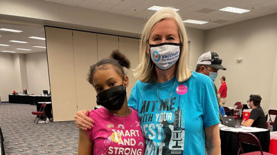 Chloe Pettus, 12, gets a hug from Margaret Powell, director of external affairs for the city of North Little Rock, after receiving her vaccination at Simmons Bank Arena.