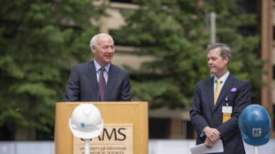Gov. Asa Hutchinson speaks Tuesday at the groundbreaking ceremony for the UAMS Radiation Oncology Center as UAMS Chancellor Cam Patterson, M.D., MBA, looks on. The expanded Radiation Oncology Center will house Arkansas’ first Proton Center, a partnership between UAMS, Baptist Health, Arkansas Children's and Proton International.