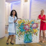 Gwendolyn Bryant-Smith, M.D., director of the Breast Center at the Winthrop P. Rockefeller Cancer Institute and Natalie Rockefeller, who serves on the institute's board of directors, prepare to see "Hope Blooms" by local artist Morgan Coven Herndon hung as one of the first three of several works are displayed in the center.