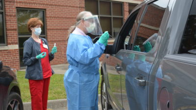 Ronald Brimberry, M.D., administers a COVID-19 test at a drive-thru testing site at the UAMS Northwest Regional Campus in Fayetteville.