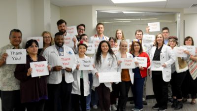 Staff and residents of the UAMS North Street Clinic in Fayetteville, Arkansas, hold up thank you signs.