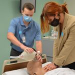 Spencer Parnell and Caroline Geels, first-year students in the College of Medicine's new 3-year M.D. program, practice CPR on a training manikin at the UAMS Northwest Regional Campus in Fayetteville.