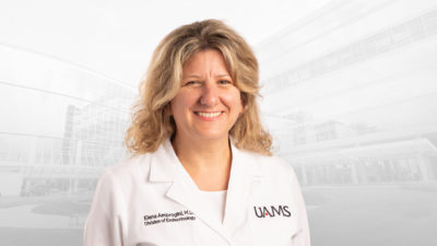 Elena Ambrogini, M.D., Ph. D., in white coat.