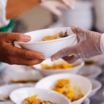 Soup kitchen staff serve food to food insecure people.