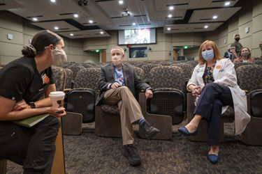 Lt. Col. Suzanne Cobleigh, left, talks to Robert Hopkins, MD, and Michelle Krause, MD, MPH., Before the start of Town Hall at UAMS.