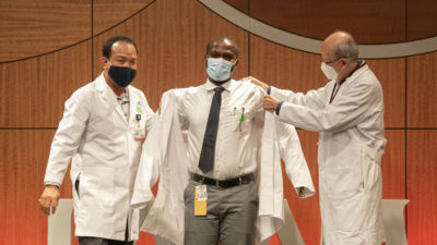 Daniel Acheampong (center) dons his white coat with assistance from Intawat Nookaew, Ph.D., and Cesar M. Compadre, Ph.D.