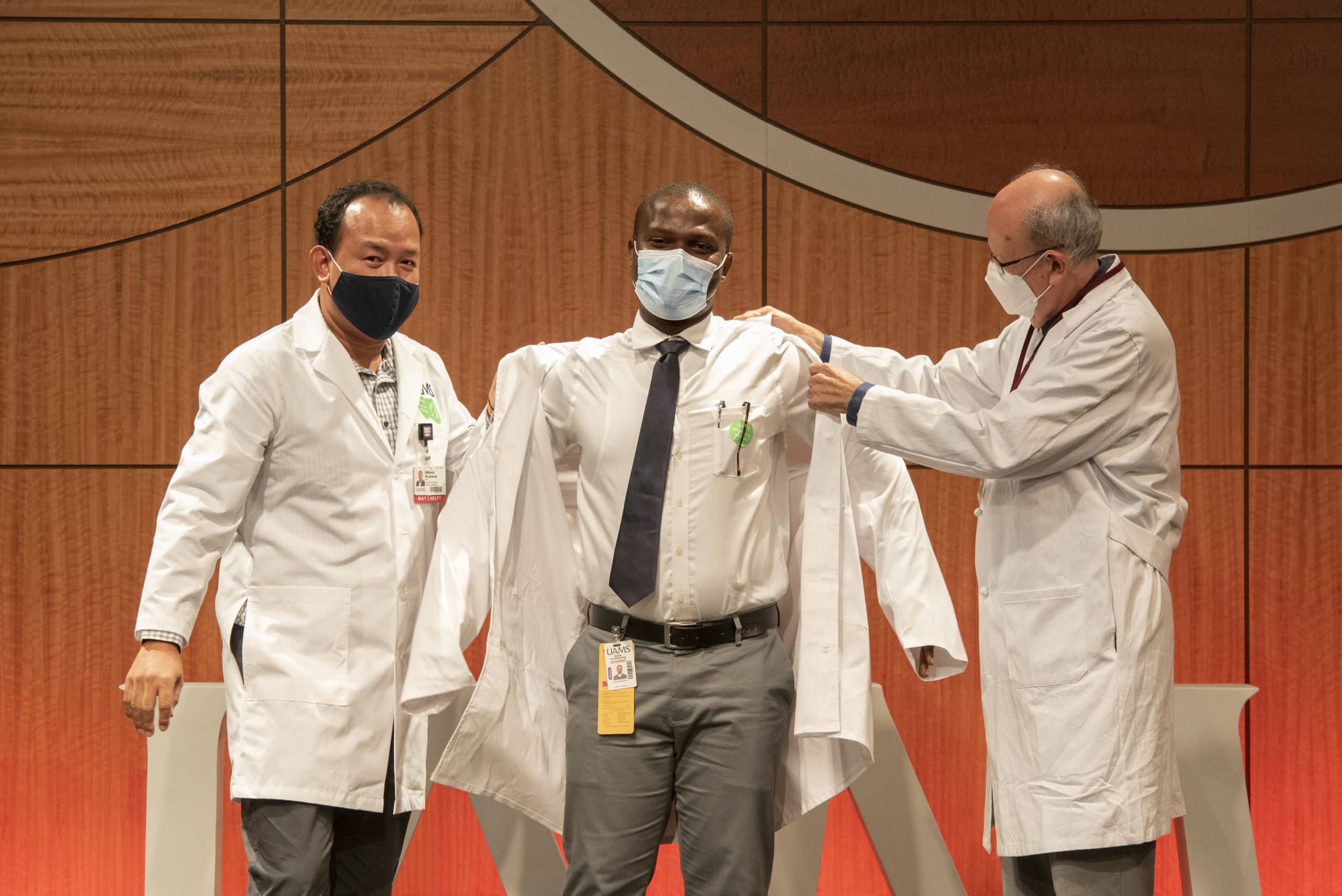 Daniel Acheampong (center) dons his white coat with assistance from Intawat Nookaew, Ph.D., and Cesar M. Compadre, Ph.D.
