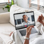 stock image of patient communicating with doctor via laptop from sofa