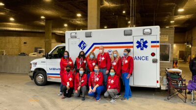 Volunteers stand in front of an ambulance