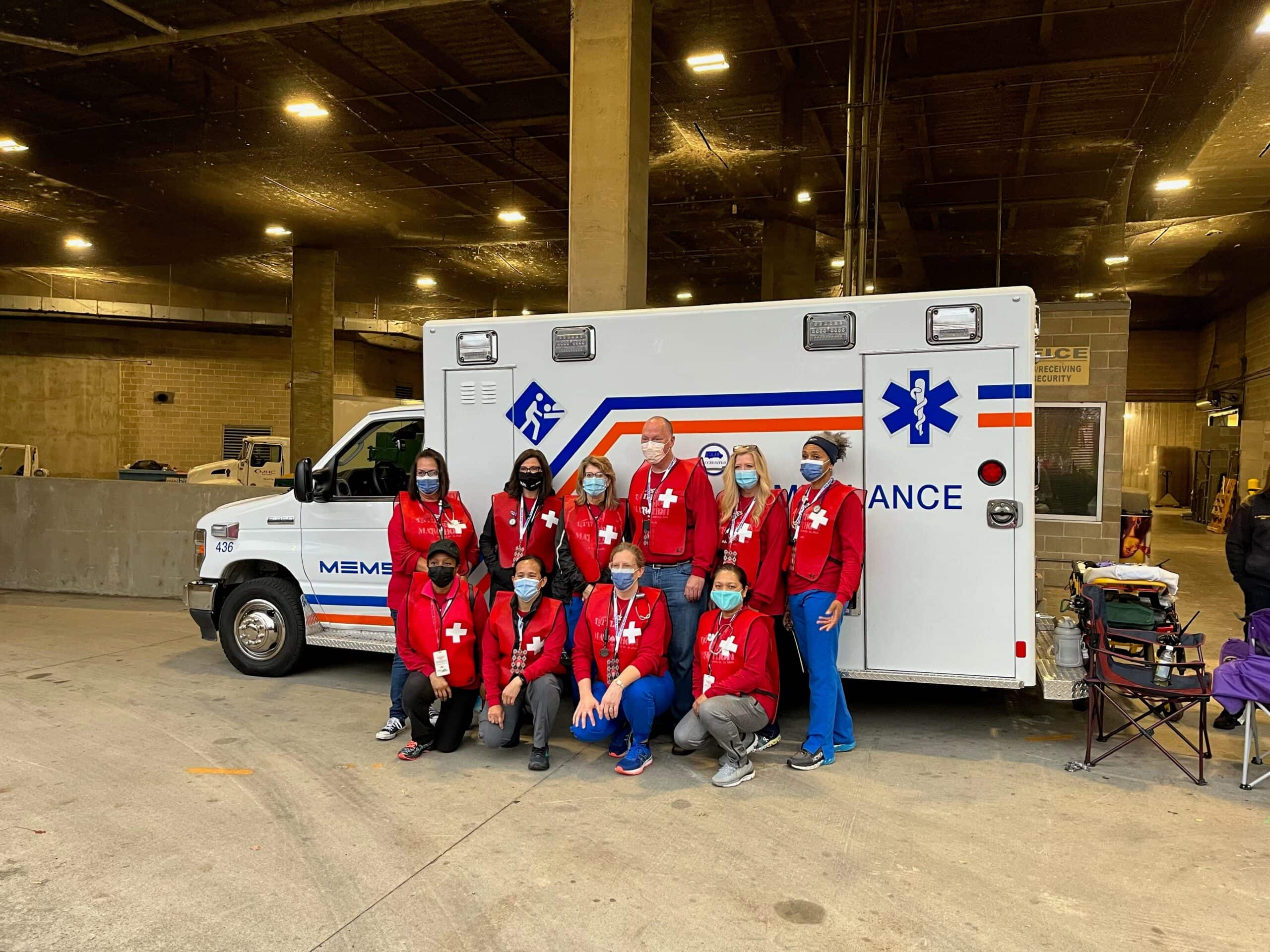 Volunteers stand in front of an ambulance