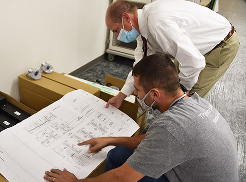 Layton Kelley, Pharm.D., right, and one of the construction contractors discuss and review one of the remodeling plans for the new pharmacy space.