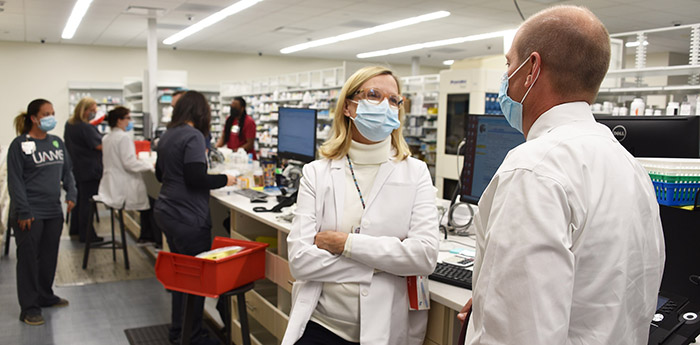 Kelley, far right, and Pattie Shuffield, Pharm.D., talk briefly in new, expanded work area of the pharmacy. Technicians and pharmacists at work in the background to fill prescriptions. 