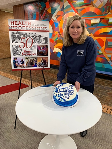 Dean Susan Long gets ready to cut into a cake to serve to celebrants of the 50th anniversary of the college's establishment.