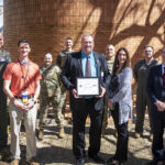 Marvin Powell, front and center, holds his Patriotic Employer Award from the Department of Defense. Also, front, left to right, Col. Dean Martin, Staff Sgt. Chris Coffman, Powell, Ms. Powell and Chancellor Cam Patterson.