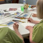 Participants in the first of five Art for Parkinson's workshops experiment with colors and mediums while music plays in the background.