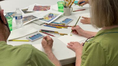 Participants in the first of five Art for Parkinson's workshops experiment with colors and mediums while music plays in the background.